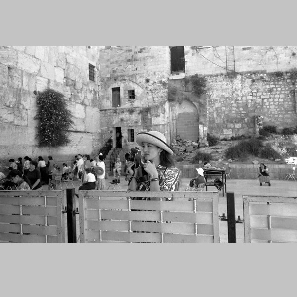 Woman holding Camera looking over fence